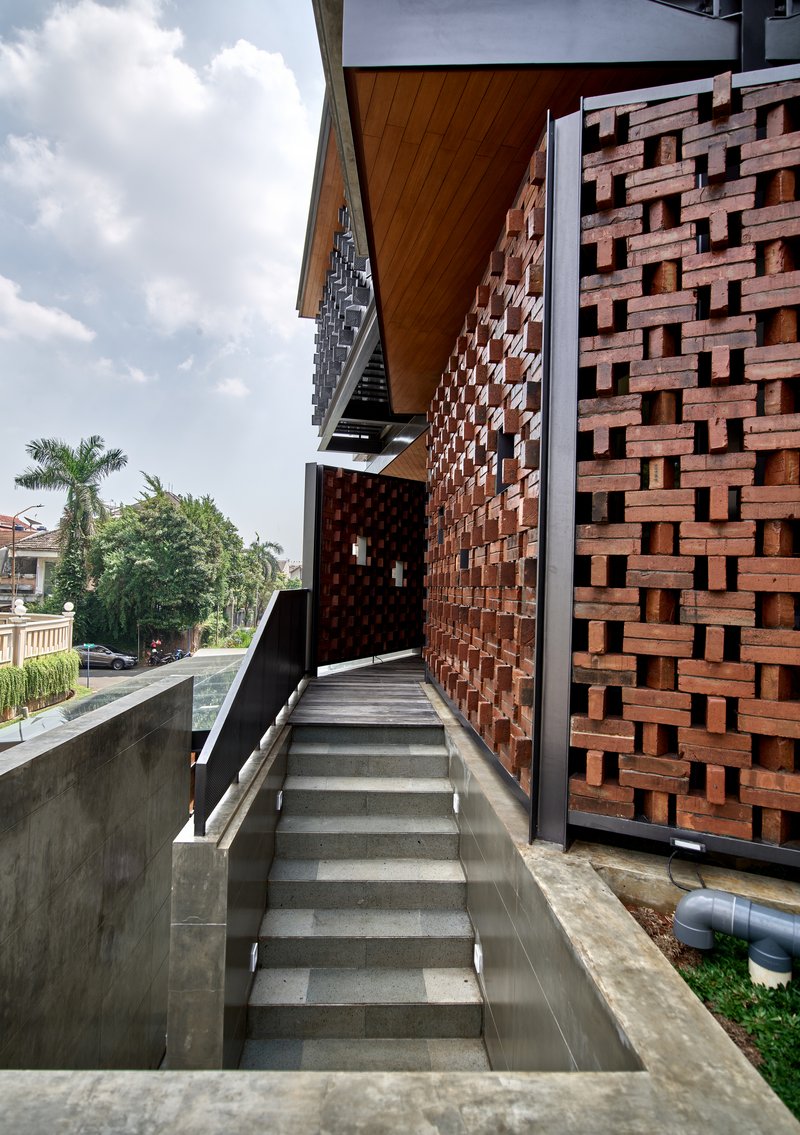 Concrete staircase running alongside a basketweave terracotta brick screen wall under cloudy skies