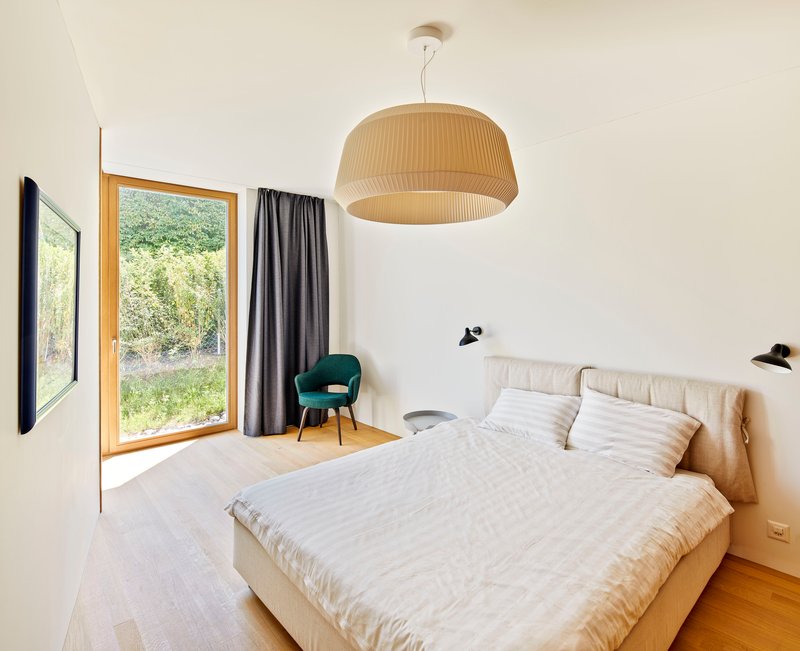 Bedroom with timber-framed window opening to a garden view and pendant light fixture overhead