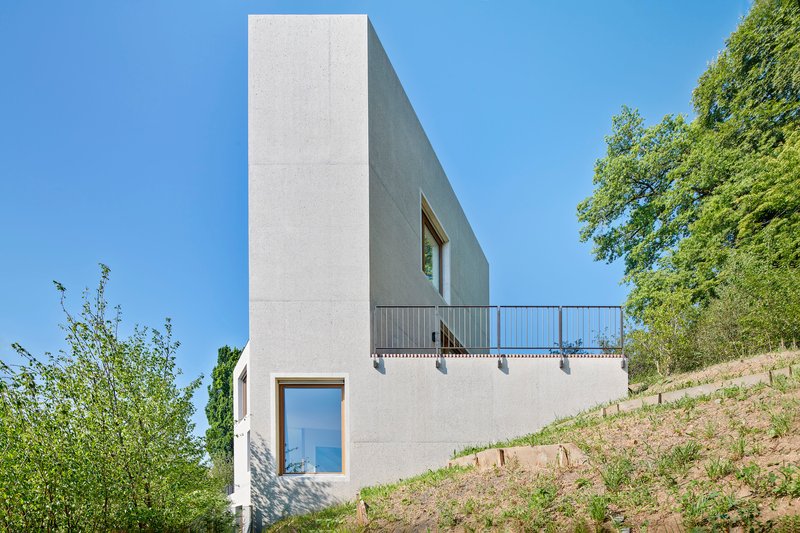 Side elevation showing punched window openings and a cantilevered terrace above terraced hillside plantings