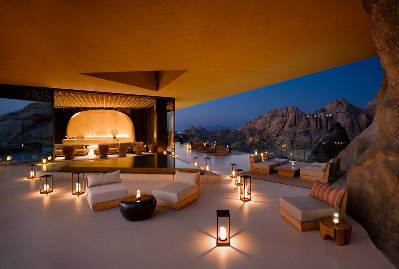 Outdoor terrace with seating and lanterns arranged around a pavilion at twilight