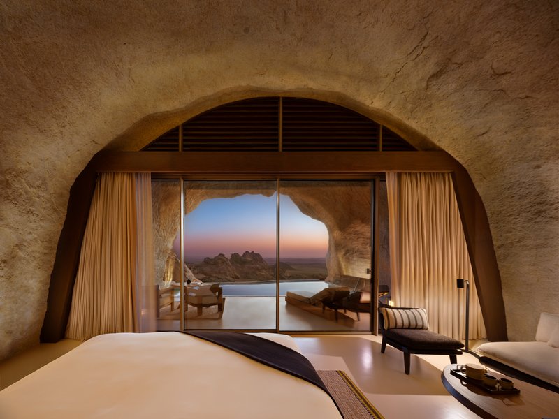 Bedroom with arched sandstone ceiling and glazed opening to pool terrace at dawn