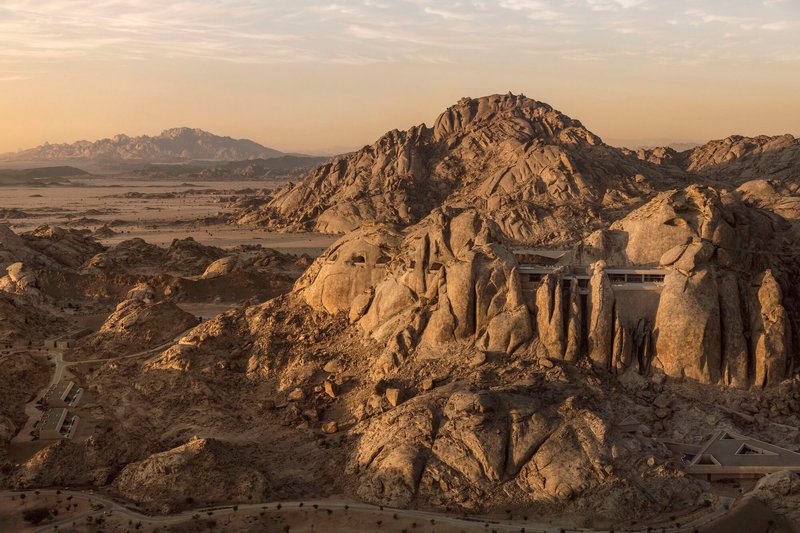 Rock-carved facade with vertical openings integrated into the desert hillside under warm afternoon light