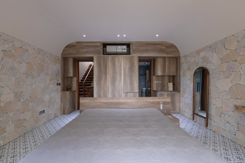 Interior space with irregular stone walls flanking a central timber alcove containing staircase and elevator