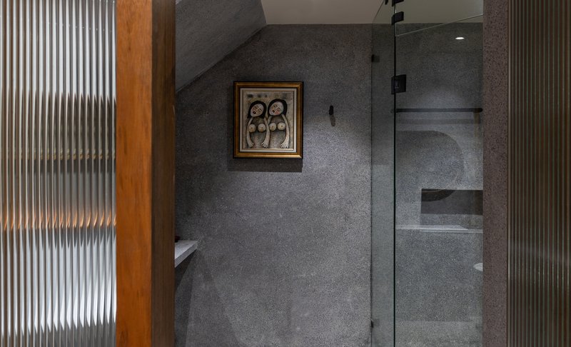 Bathroom corner with fluted glass partition and recessed shower niche in grey terrazzo walls