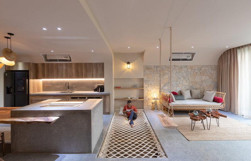 Open living area with kitchen island, irregular stone accent wall and child sitting on patterned rug