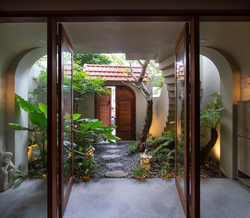 View through open timber doors into courtyard garden with arched white walls framing the passage