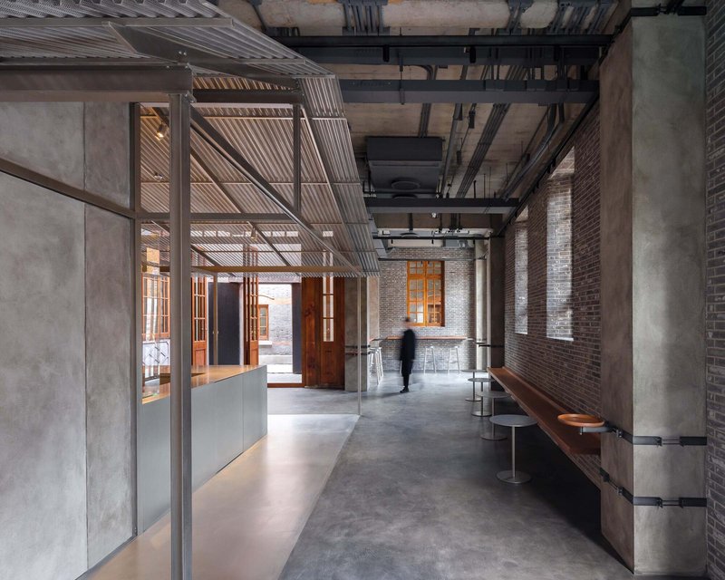 Interior corridor with exposed brick walls, concrete columns, suspended timber slat ceiling and polished concrete floor
