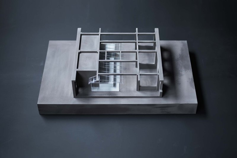 Physical model revealing interior spatial organization through transparent acrylic walls and steel frame