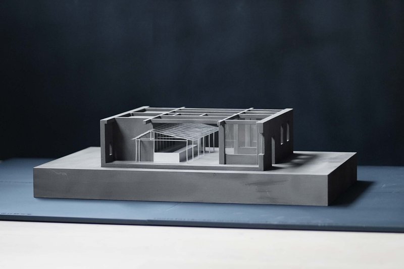 Physical model showing the gabled roof structure with exposed timber framing and interior courtyard