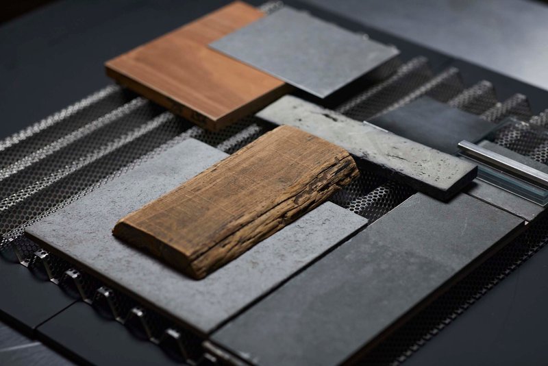 Material sample board with timber, concrete, metal mesh, and stone arranged on woven textile
