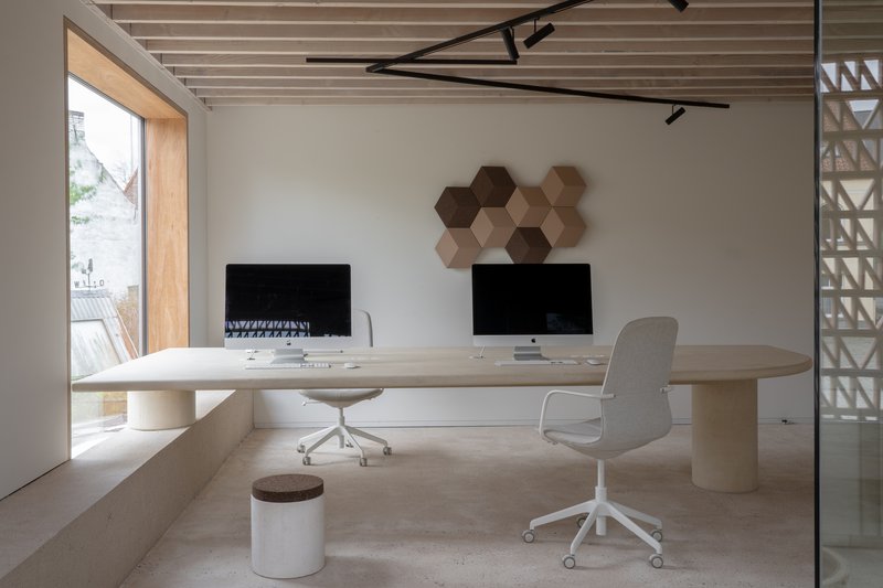 Office with light wood desk, exposed timber ceiling joists and hexagonal wall panels