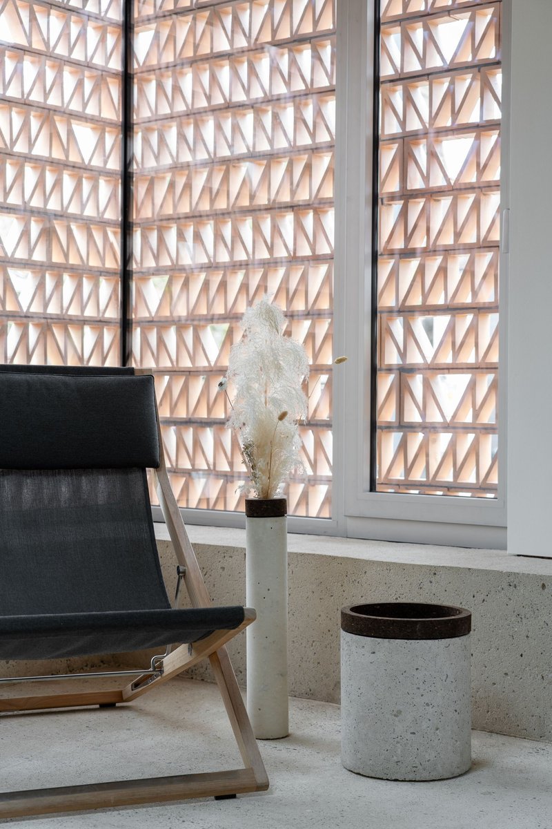 Timber lattice screen with triangular pattern filtering daylight into the terrazzo-floored interior