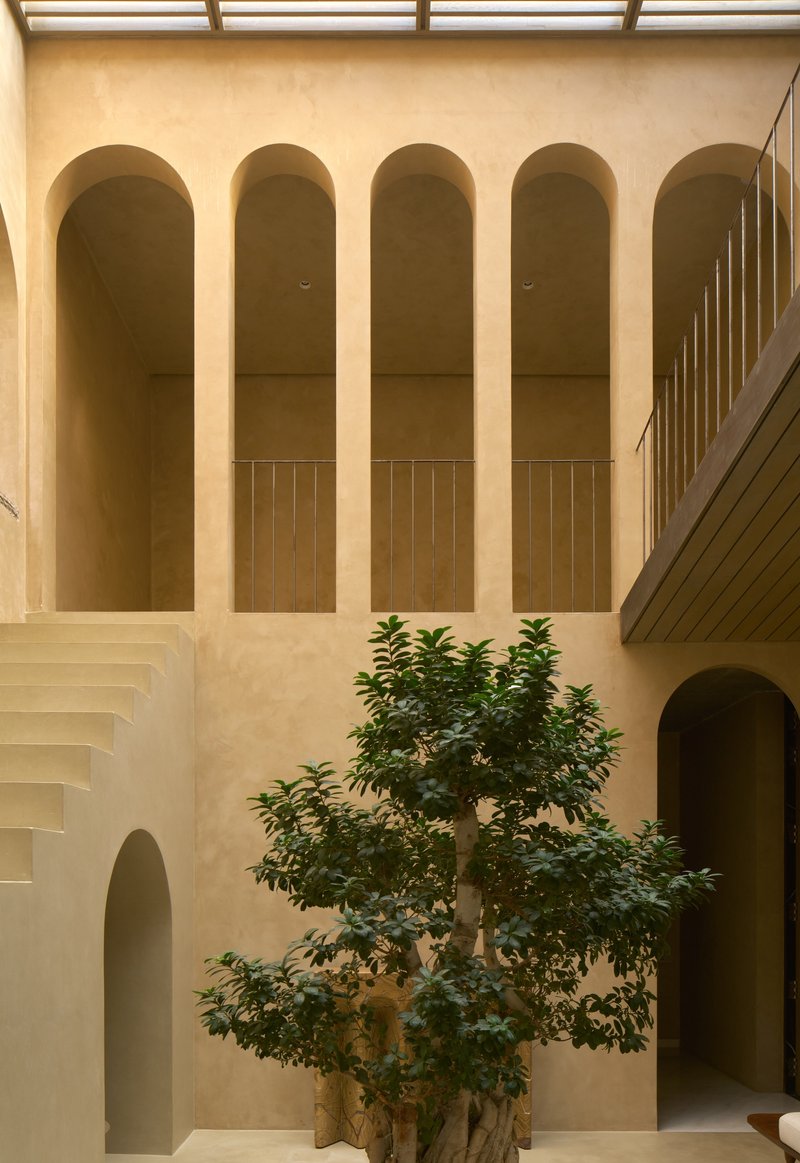 Interior courtyard wall with five arched niches and timber-paneled balustrades surrounding a central tree