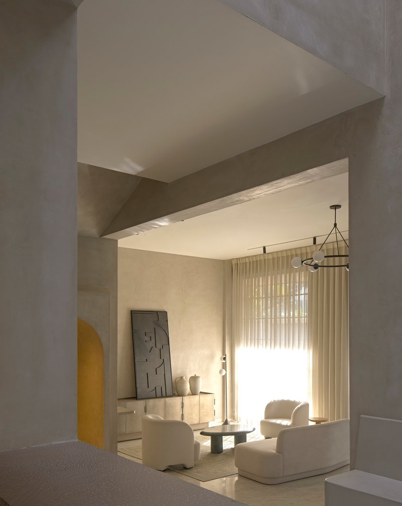 View through arched threshold into living room with sheer curtains filtering afternoon light