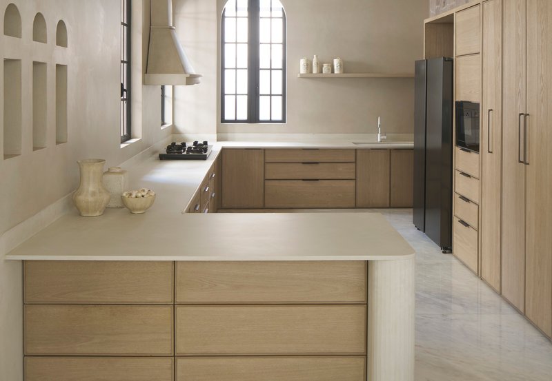 Kitchen with oak cabinetry and island beneath arched window with steel frame muntins