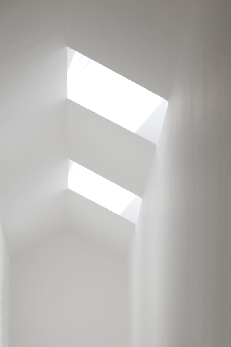 Two angled skylights punched through a white plaster ceiling casting soft natural light