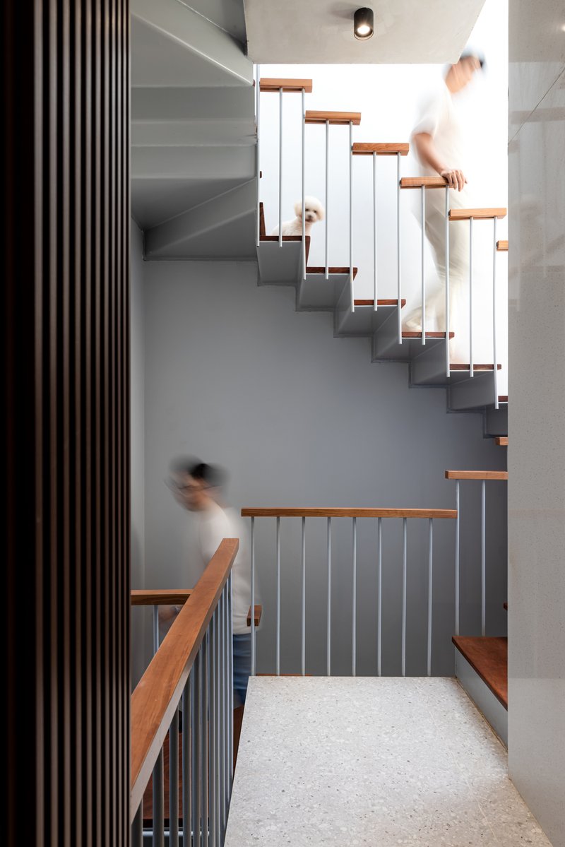 Cantilevered staircase with timber treads and vertical balustrade showing figures in motion passing through