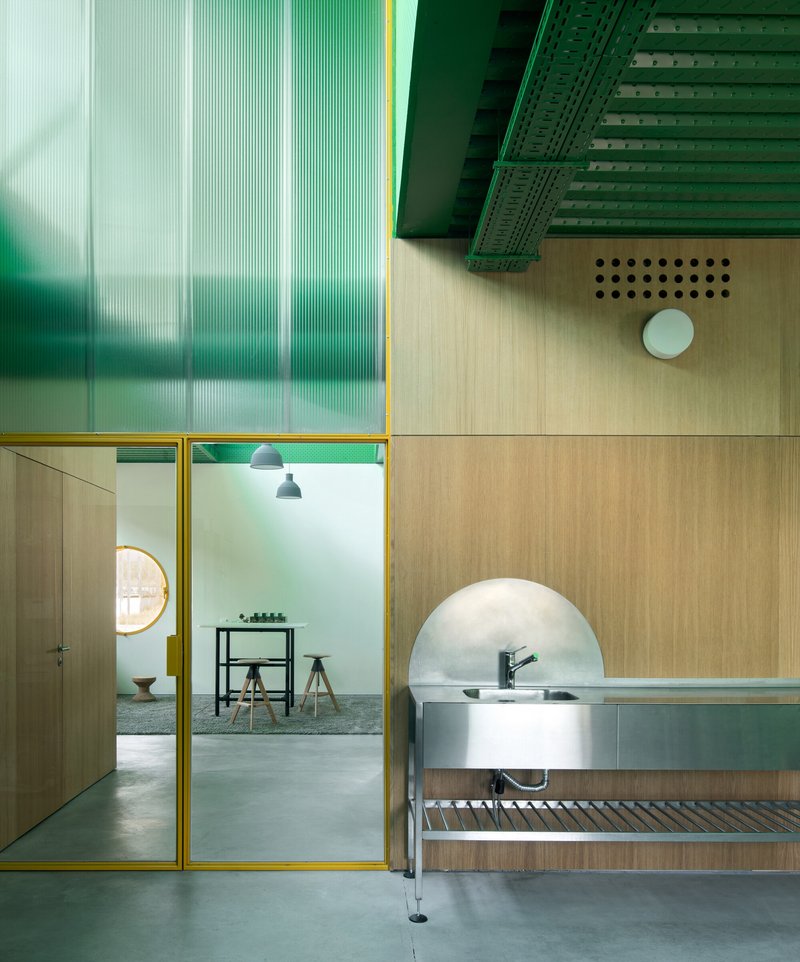 Top-down view of a sink unit beneath translucent green panels and yellow-framed glass partitions on polished concrete