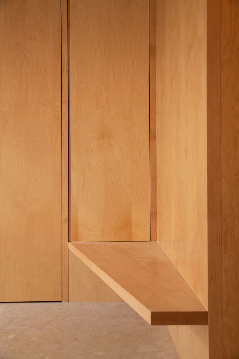 Detail of recessed timber panel corner meeting a stone floor in warm natural light