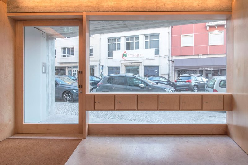 Interior timber-framed storefront with built-in bench looking out to a cobblestone street with parked cars