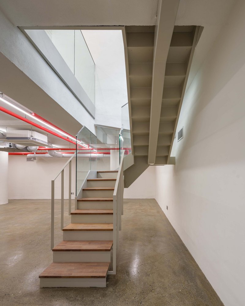 Open-tread staircase with timber treads and glass balustrade beneath a white coffered ceiling