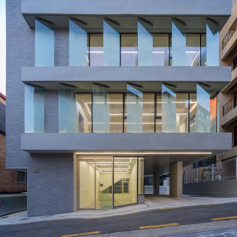 Front elevation with cantilevered balconies, glass glazing and a ground-level entrance at twilight