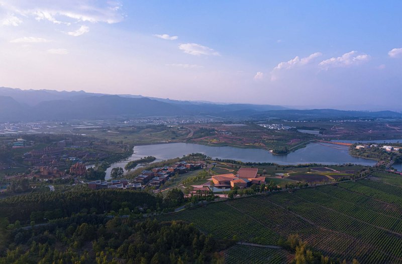 Distant aerial view of the complex nestled between lake and mountains at twilight