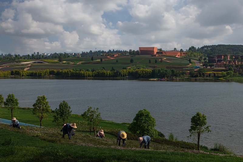 Distant view across the water of the compound on planted terraces under afternoon clouds