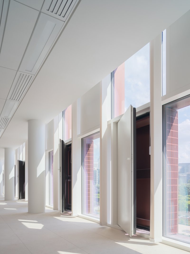 White corridor with deep-set windows and column coffers casting afternoon shadows across the floor