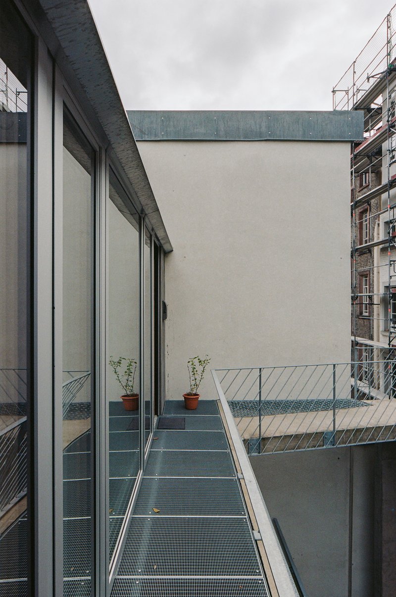 Metal grate walkway with potted plants and white railing under an overcast sky