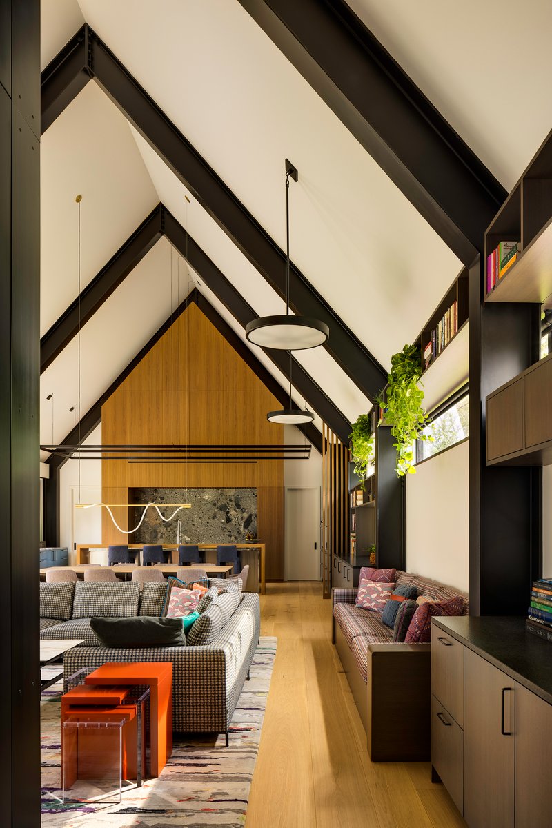 Double height living space with exposed black rafters and pendant lights above seating areas