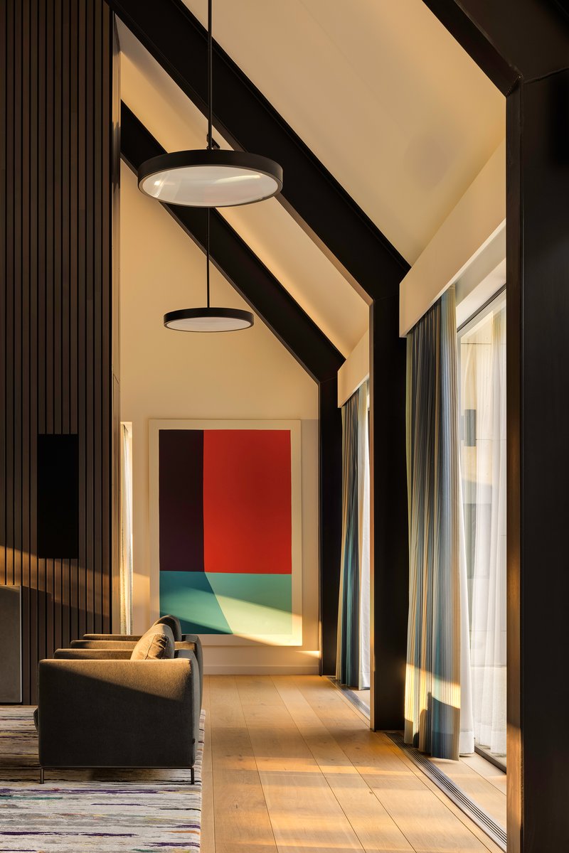 Corridor with exposed black rafters and warm afternoon light streaming through glazed walls