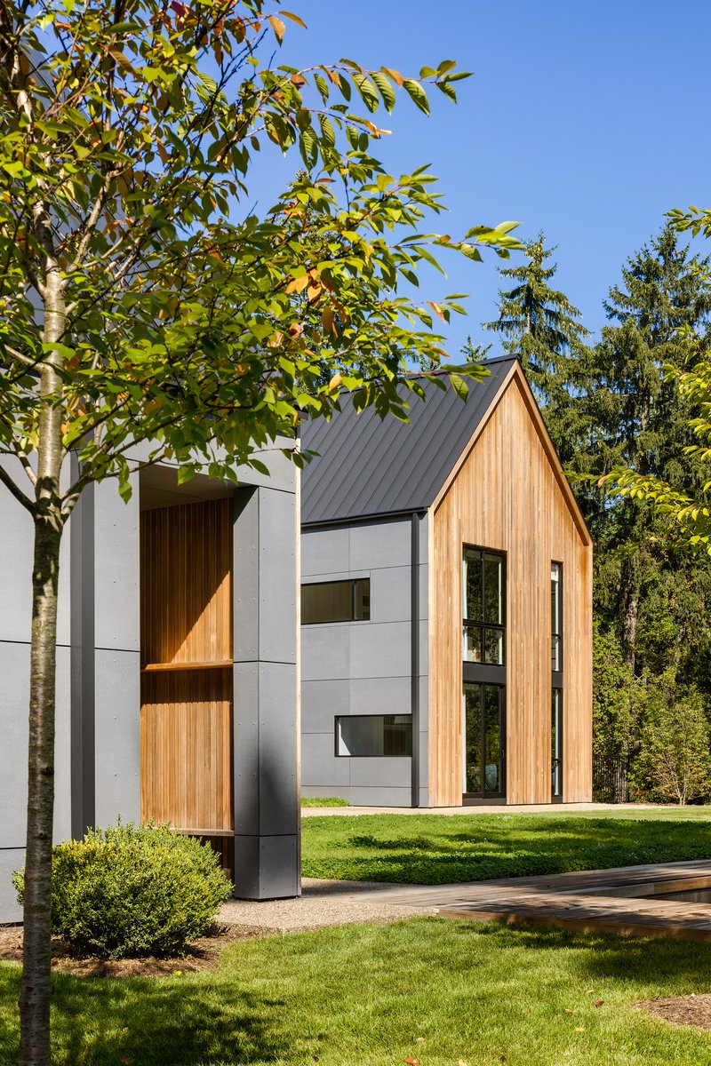 Street view of the paired gable forms combining vertical timber cladding and white panels in afternoon light
