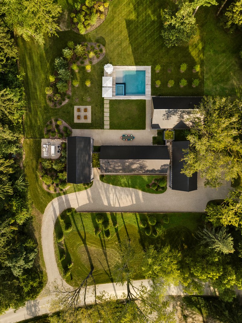 Top-down view showing curved gravel drive, courtyard spaces and scattered tree shadows on the ground