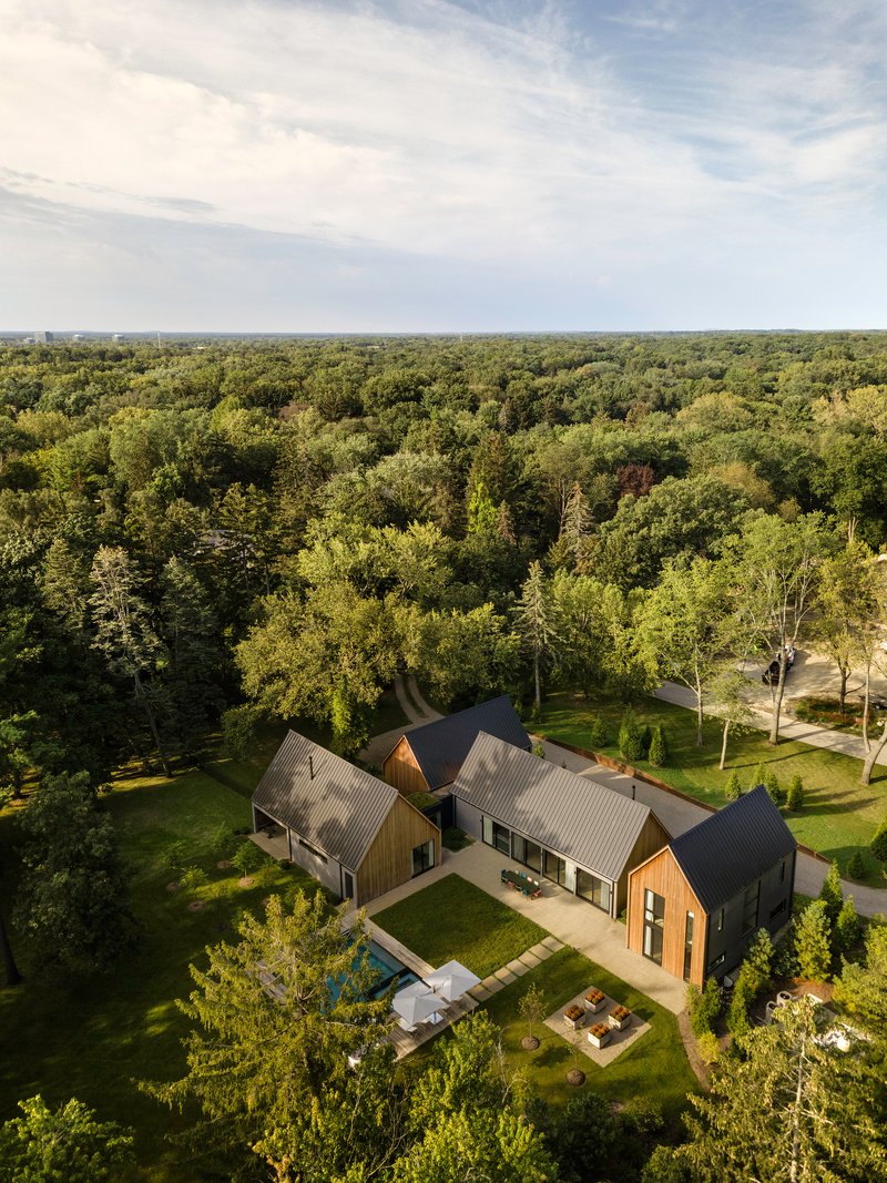 Drone view of the compound with rear terrace and lawn surrounded by dense forest