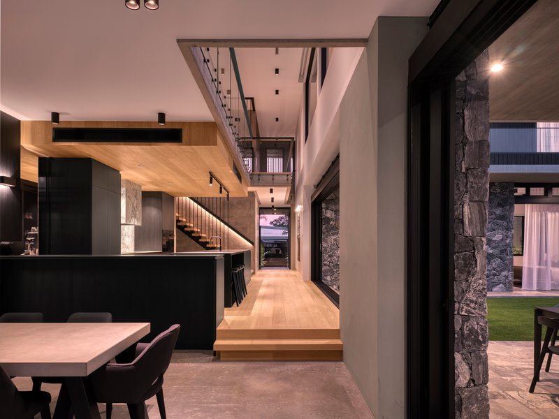 Interior hallway with timber flooring leading to illuminated staircase beneath mezzanine level