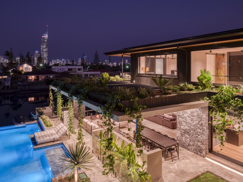 Multi-level terrace with planted beds, outdoor dining area, and pool at twilight with distant skyline