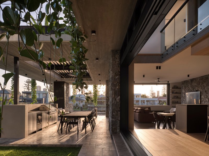 Courtyard dining area with stone column, hanging plants and low afternoon sunlight streaming through