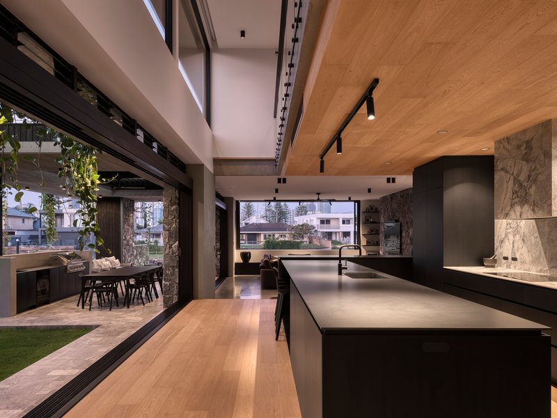 Open-plan kitchen and dining area with sliding glass walls opening to outdoor terrace and planted vines