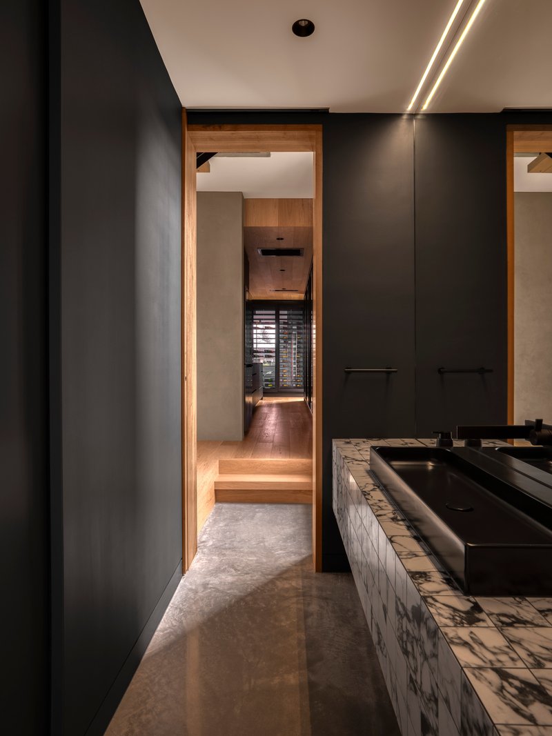 Corridor with black millwork and timber-framed doorway leading to stepped interior spaces beyond
