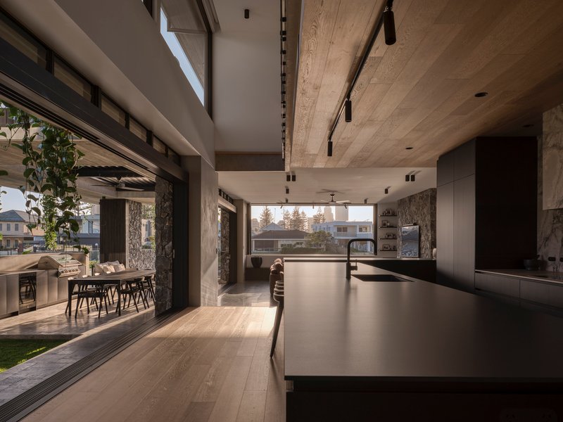 Kitchen island with view through multiple sliding glass doors to outdoor dining terrace at dusk