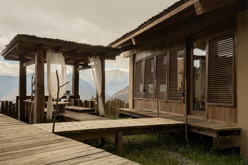 Raised timber deck with covered pavilion, louvered shutters and mountain range in the distance