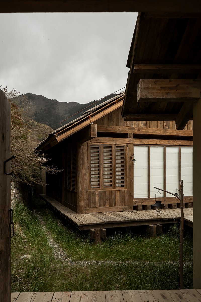 Timber cabin with louvered shutters and sliding screens on raised deck under overcast sky