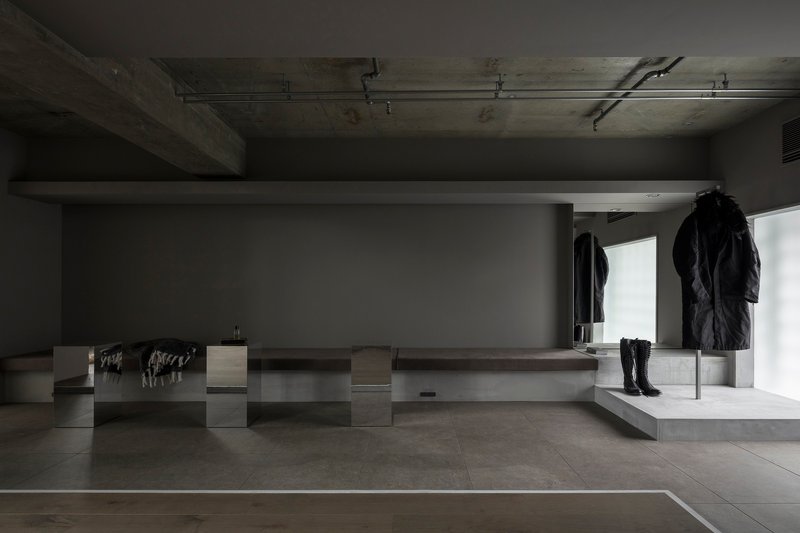 Retail display pedestals with garments beneath exposed concrete ceiling and recessed lighting