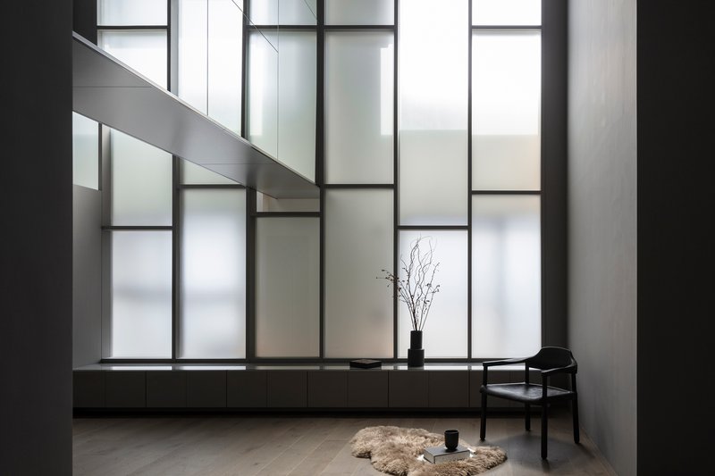 Gridded translucent glass wall with backlit panels above a continuous low platform along the floor
