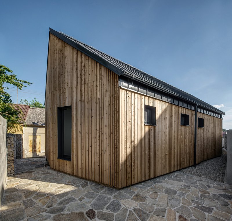 Long elevation of vertical timber cladding with square window openings and clerestory glazing