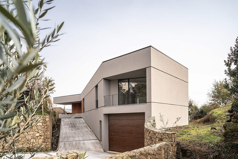 Angular massing defining a modern hillside residence with integrated garage access.