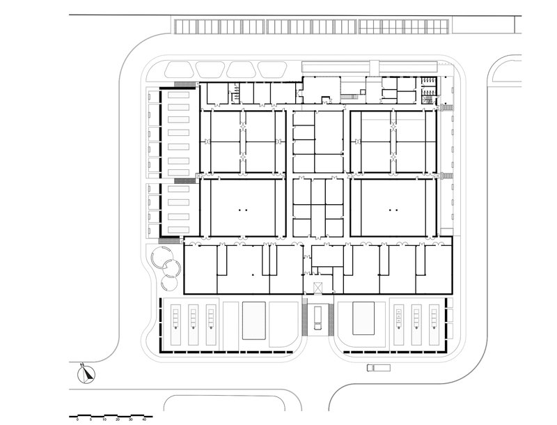 Ground floor plan drawing showing a rectangular building organized around four interior courtyards with parking