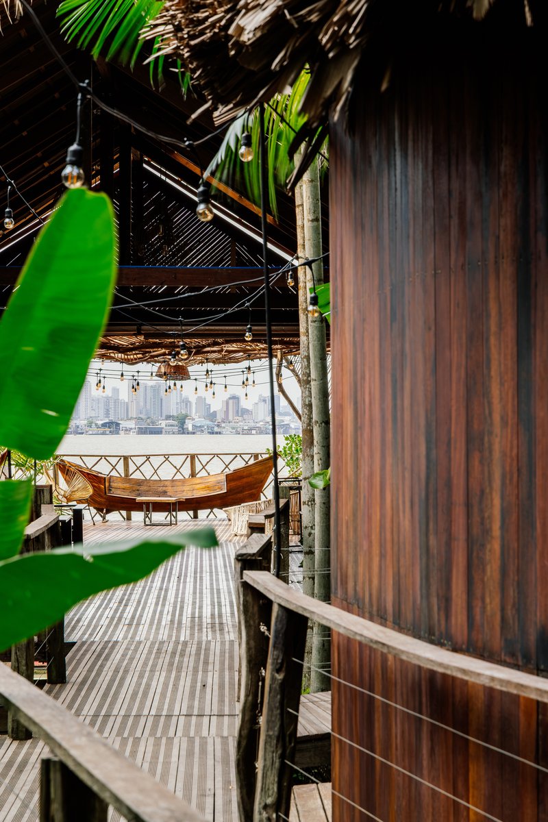 Weathered timber wall panel beside raised deck with glimpse of interior dining space beyond