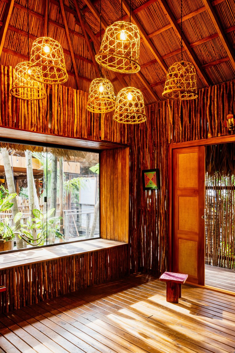 Corner with woven pendant lamps above a timber window bench with dappled sunlight on the wood floor